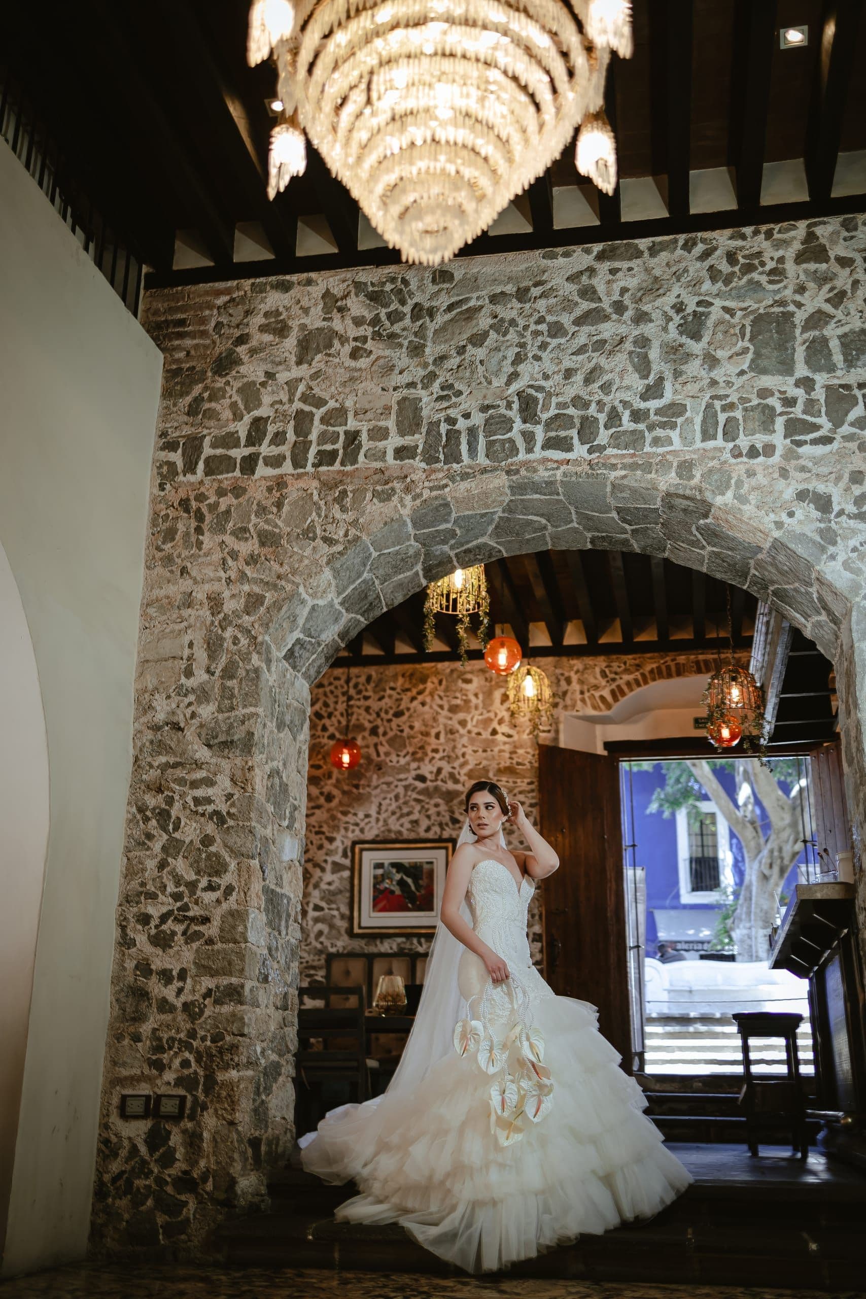 Novia bajo un arco de piedra iluminado con candil, en una casona de Puebla