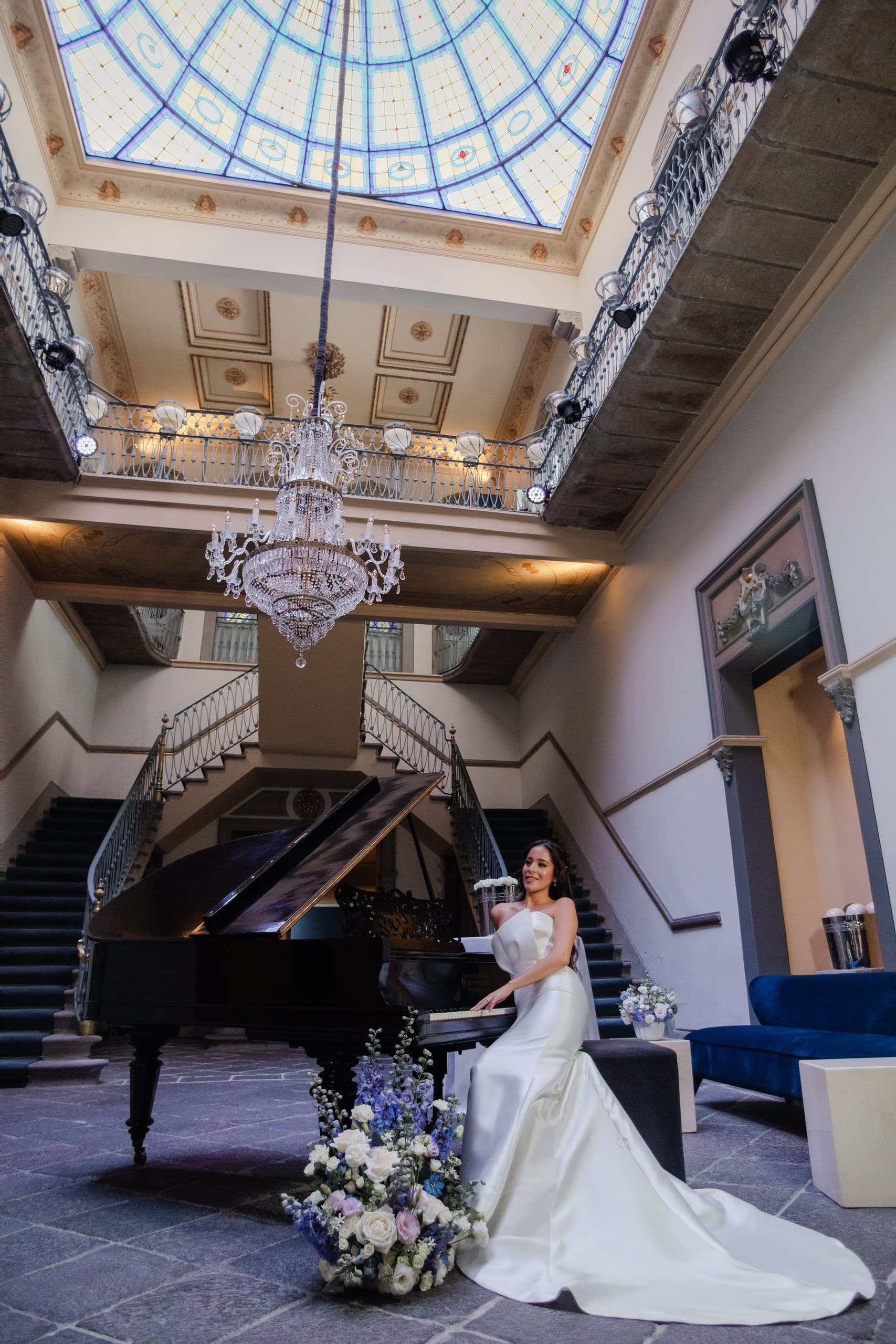 Novia bajo la cúpula de cristal emplomado de una casona, junto a un piano de cola