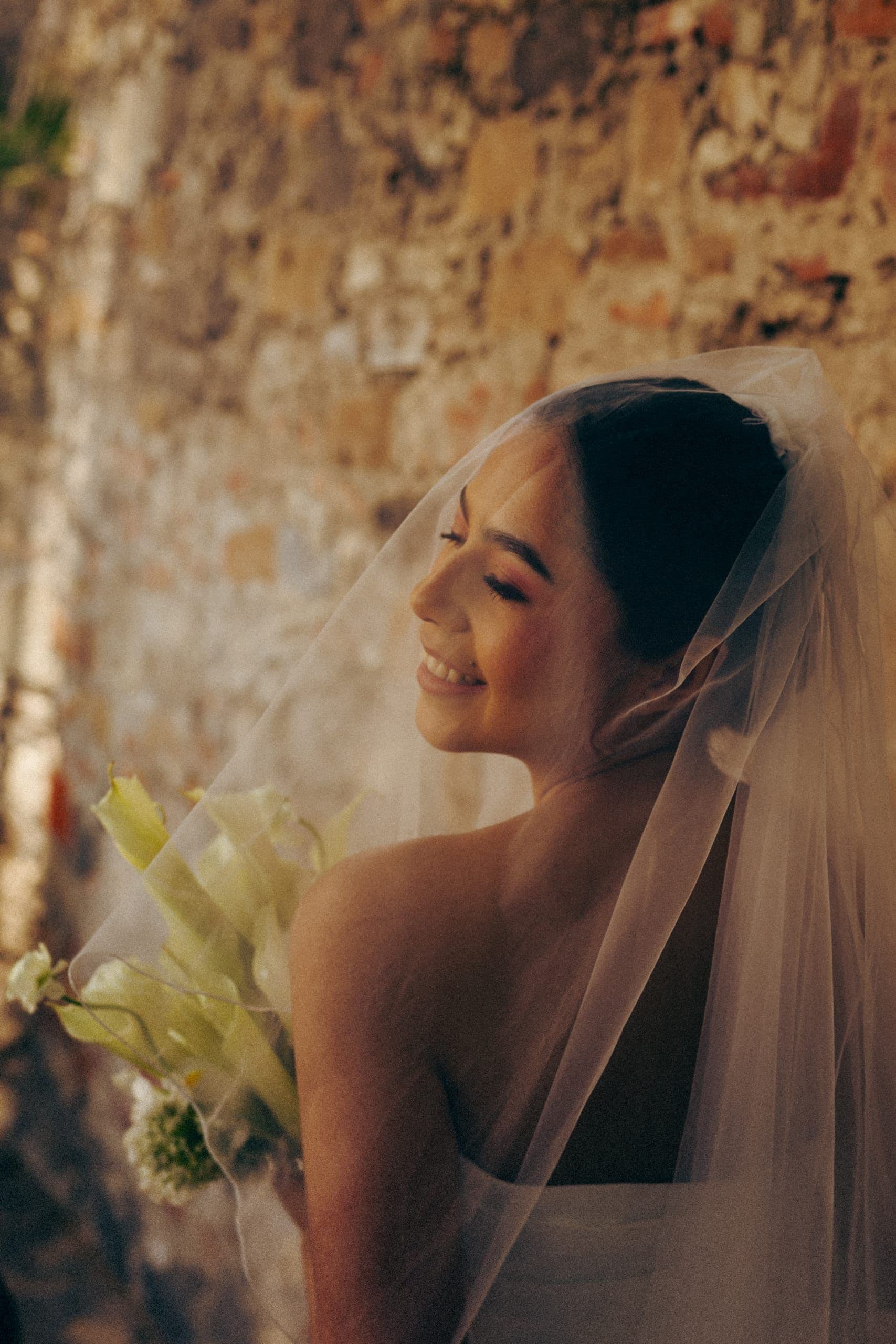 Novia sonriendo tras su velo a contraluz, el día de su boda en Puebla