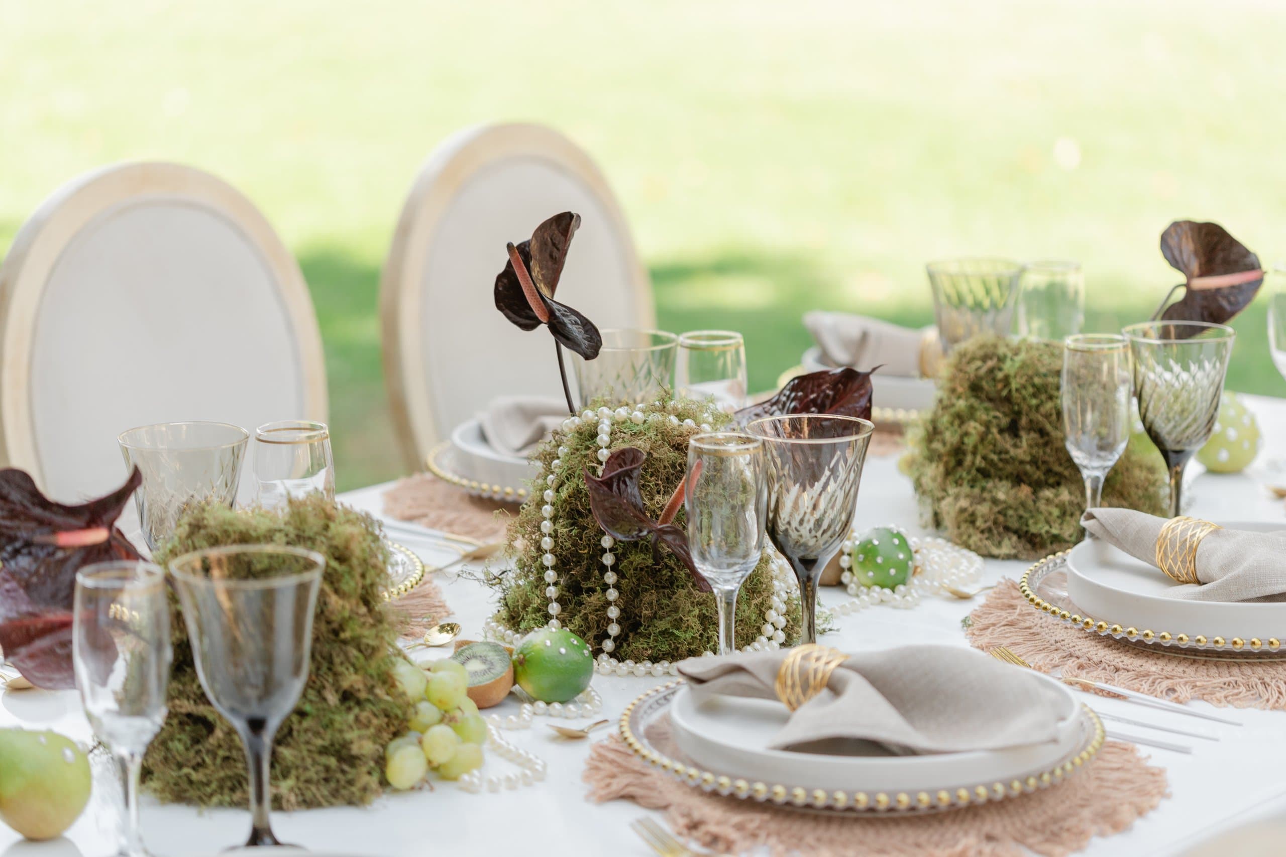 Servicio de mesa al aire libre con musgo, perlas y uvas, montaje botánico de Clhei