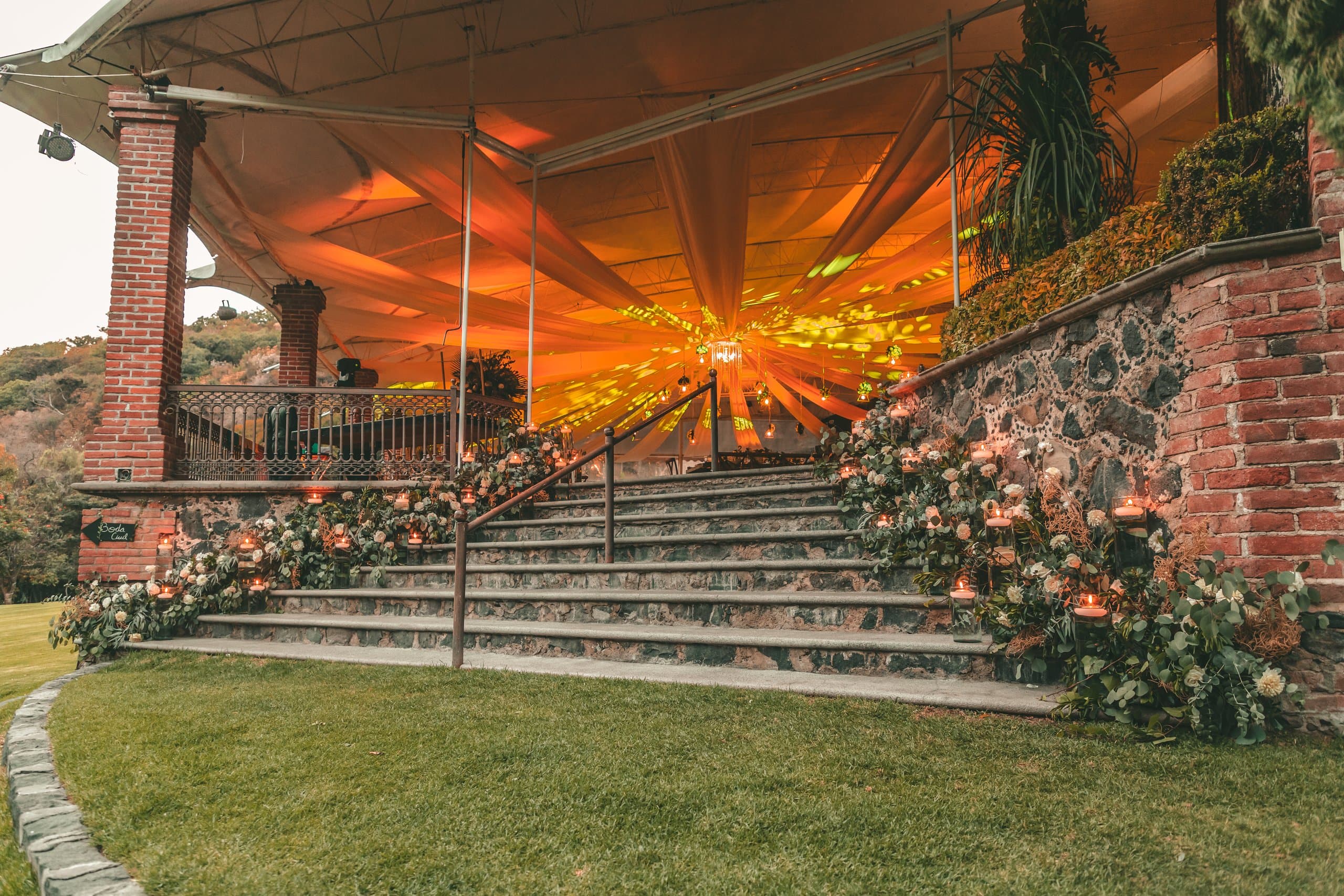 Escalinata de hacienda flanqueada de flor, con el cielo naranja al atardecer