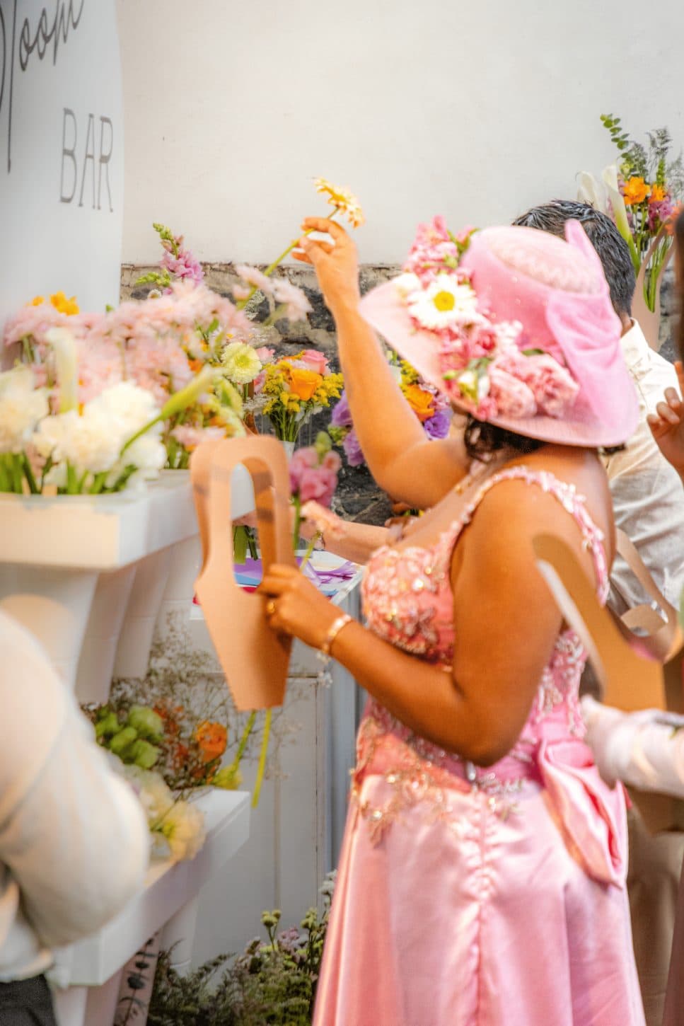 A guest in a hat picks a gerbera at the Flower Bar during the celebration