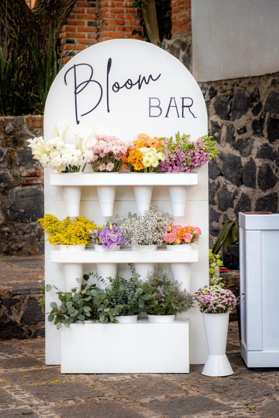 Clhei's Bloom Bar stand with buckets of flowers by color: callas, daisies, gerberas, solidago, lisianthus and eucalyptus