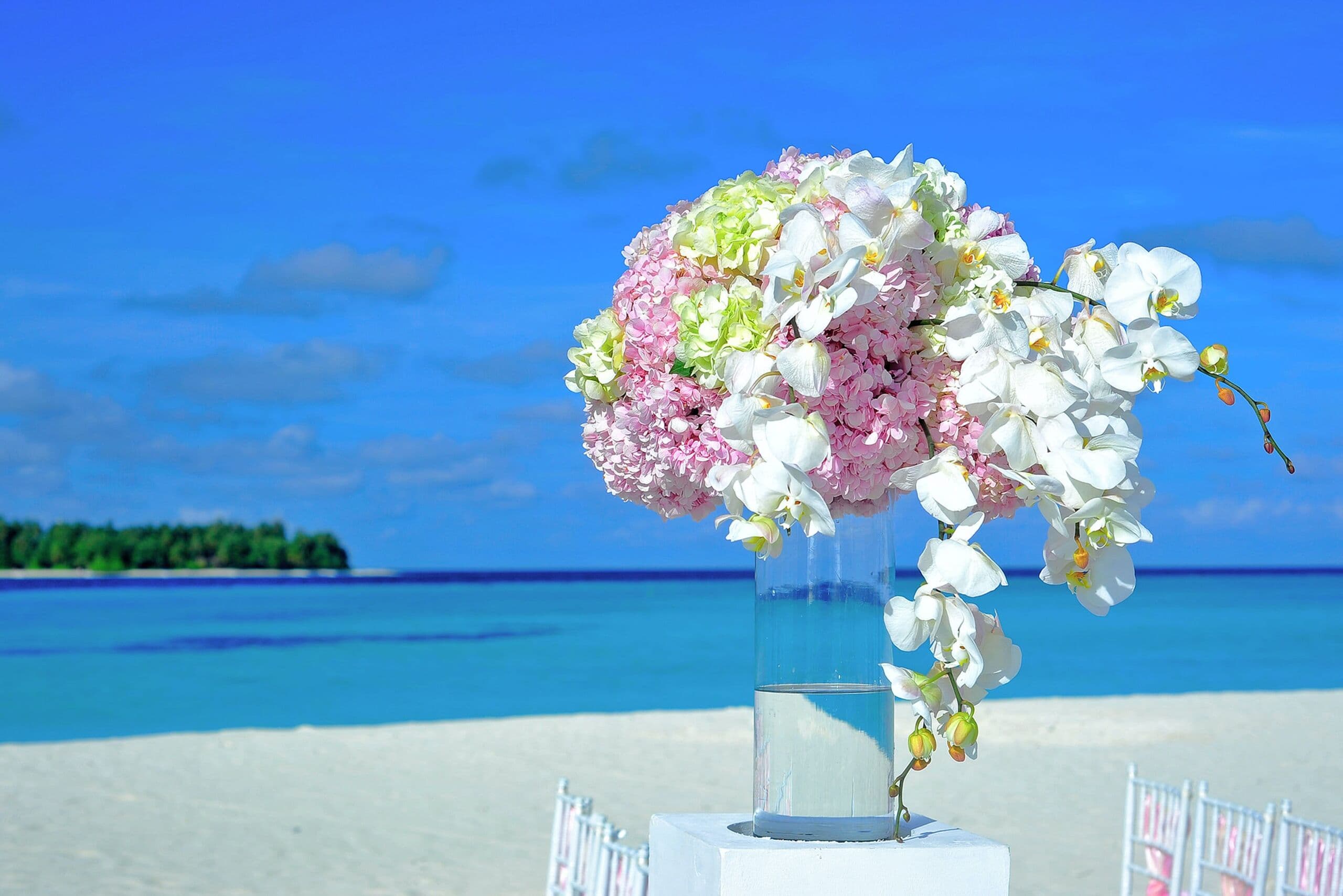 Arreglo floral de boda en blancos y rosas sobre un pedestal frente al mar
