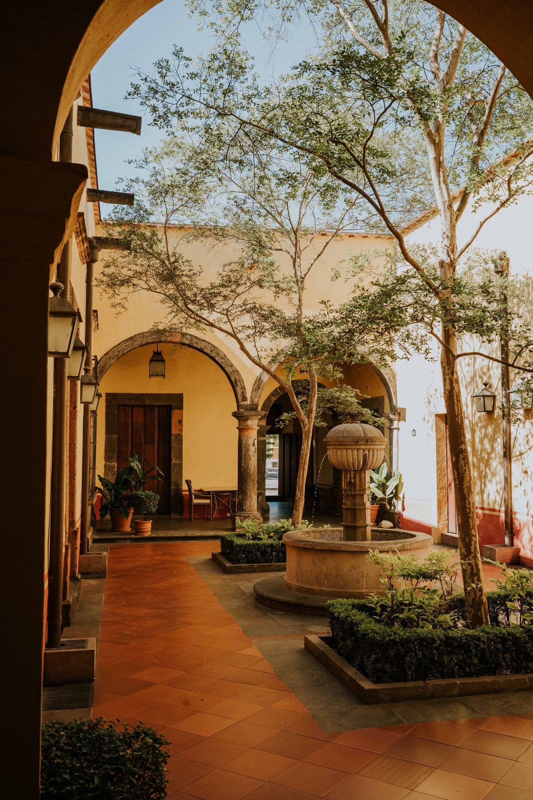 Stone courtyard of a Mexican hacienda with arches, a fountain and terracotta floors
