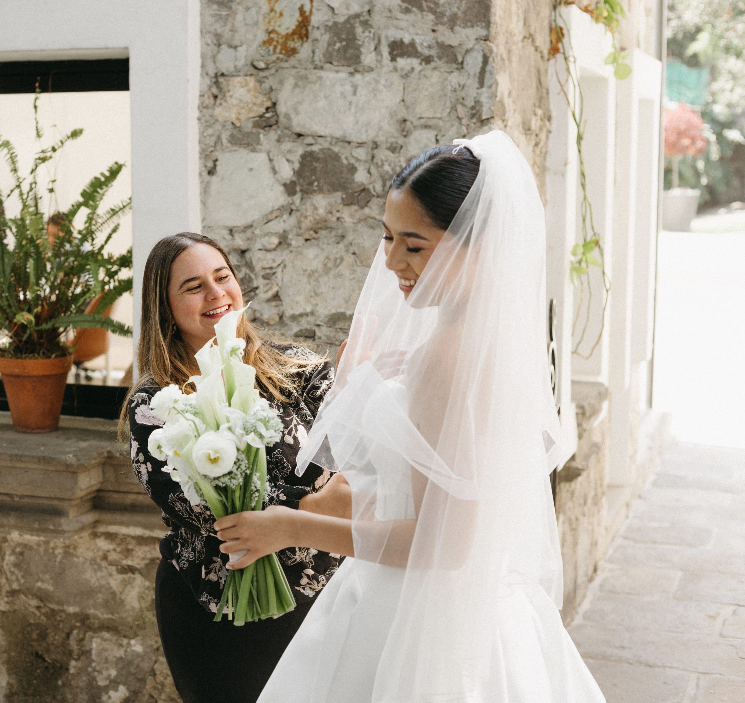 El equipo Clhei ajusta el velo de una novia y le entrega su ramo de calas