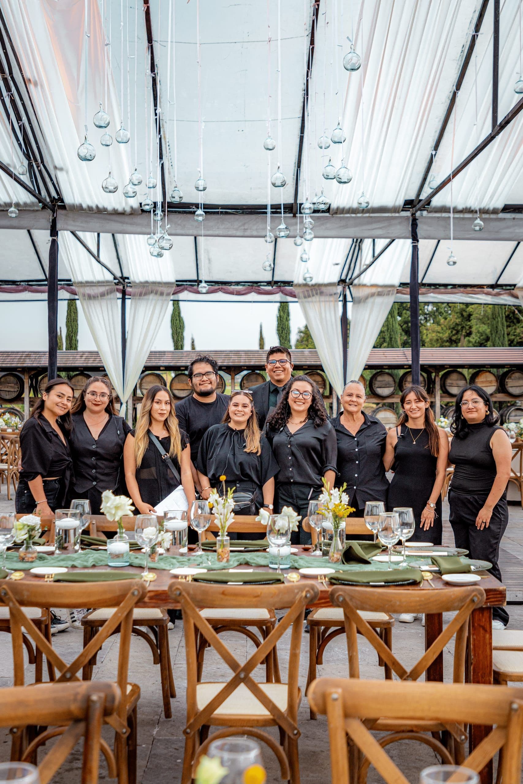 El equipo de Clhei reunido tras una mesa montada, vestido de negro, en un viñedo de Puebla