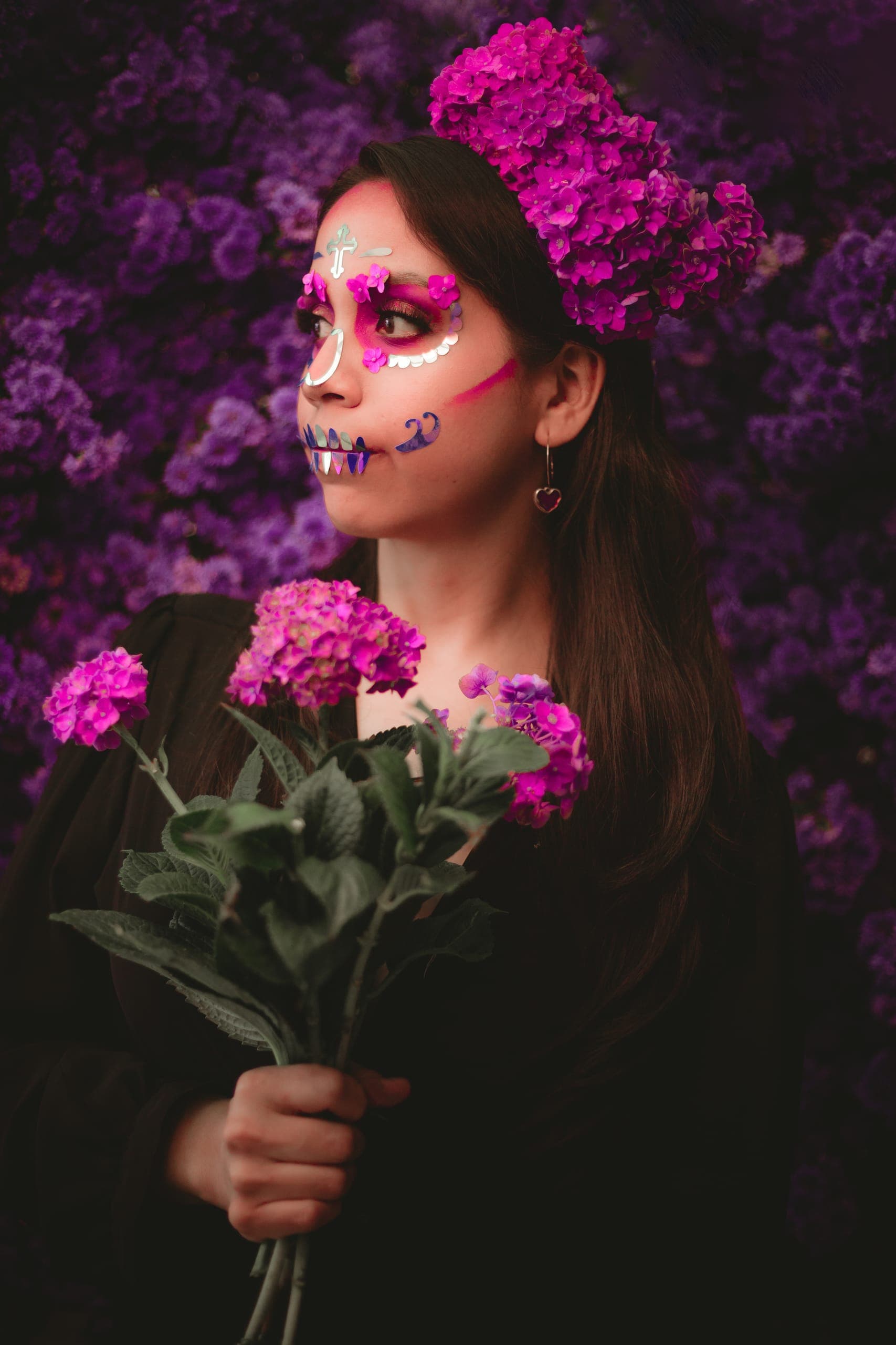 Catrina sosteniendo tallos de hortensia frente al muro floral
