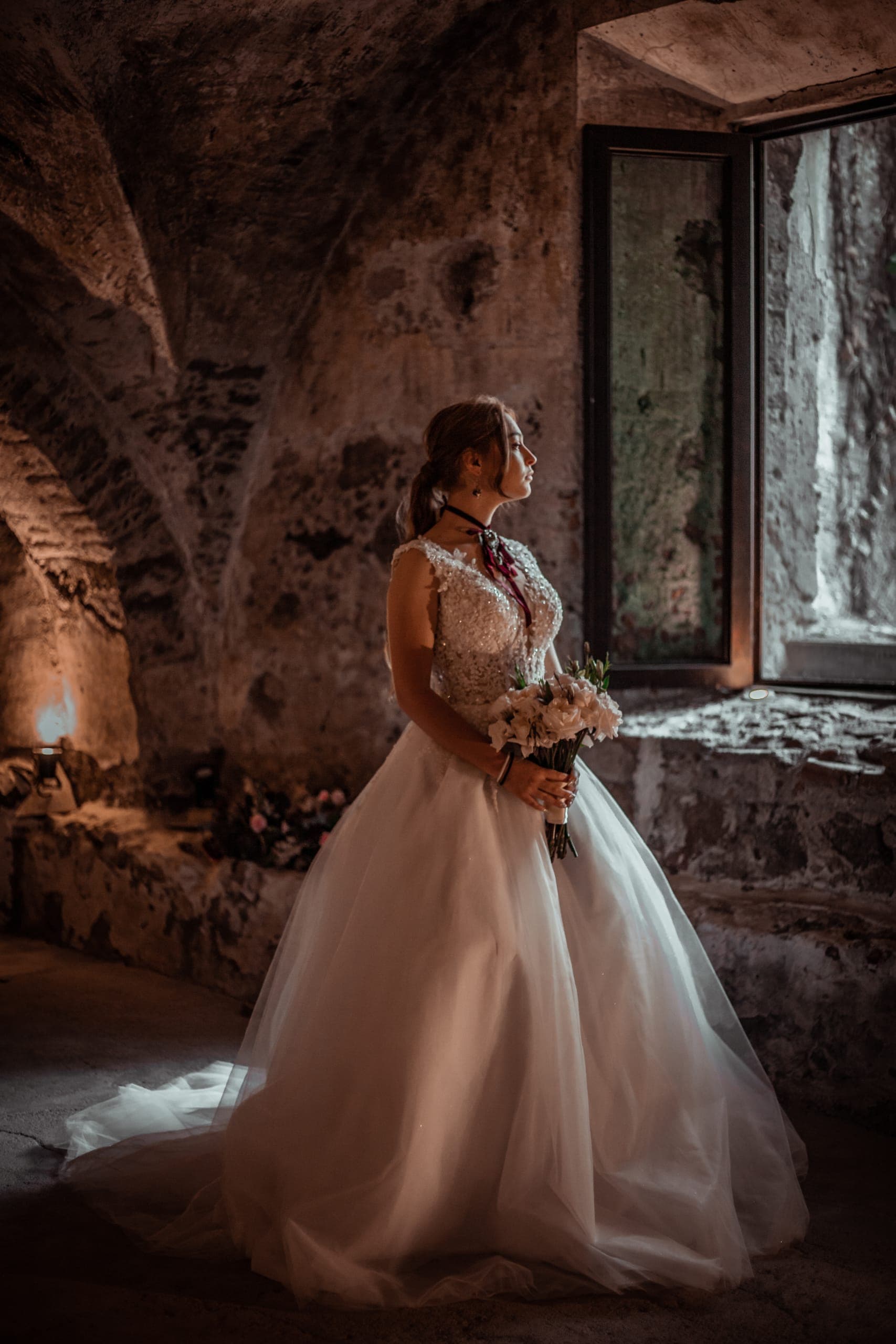 Novia con su ramo bajo los arcos de piedra de la hacienda