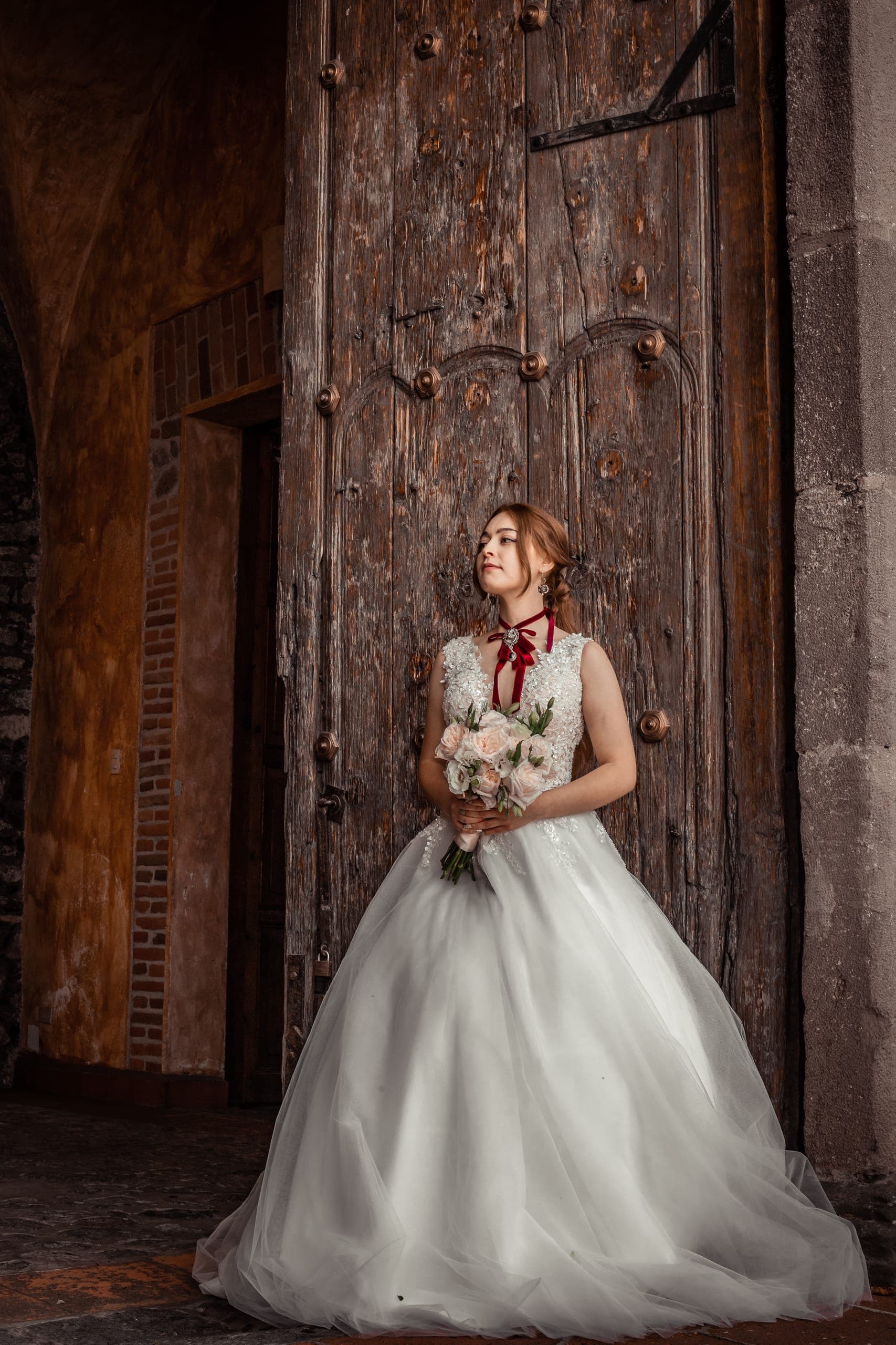 Novia con ramo frente a una puerta antigua de la hacienda