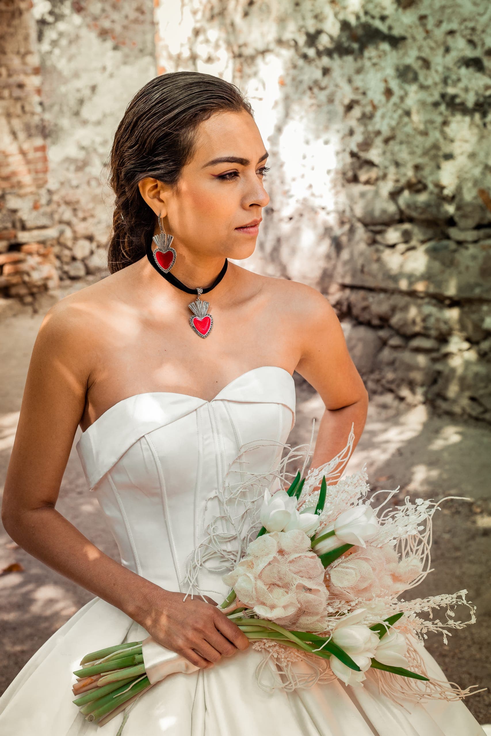 Novia con gargantilla de corazón y ramo de flor clara en el jardín