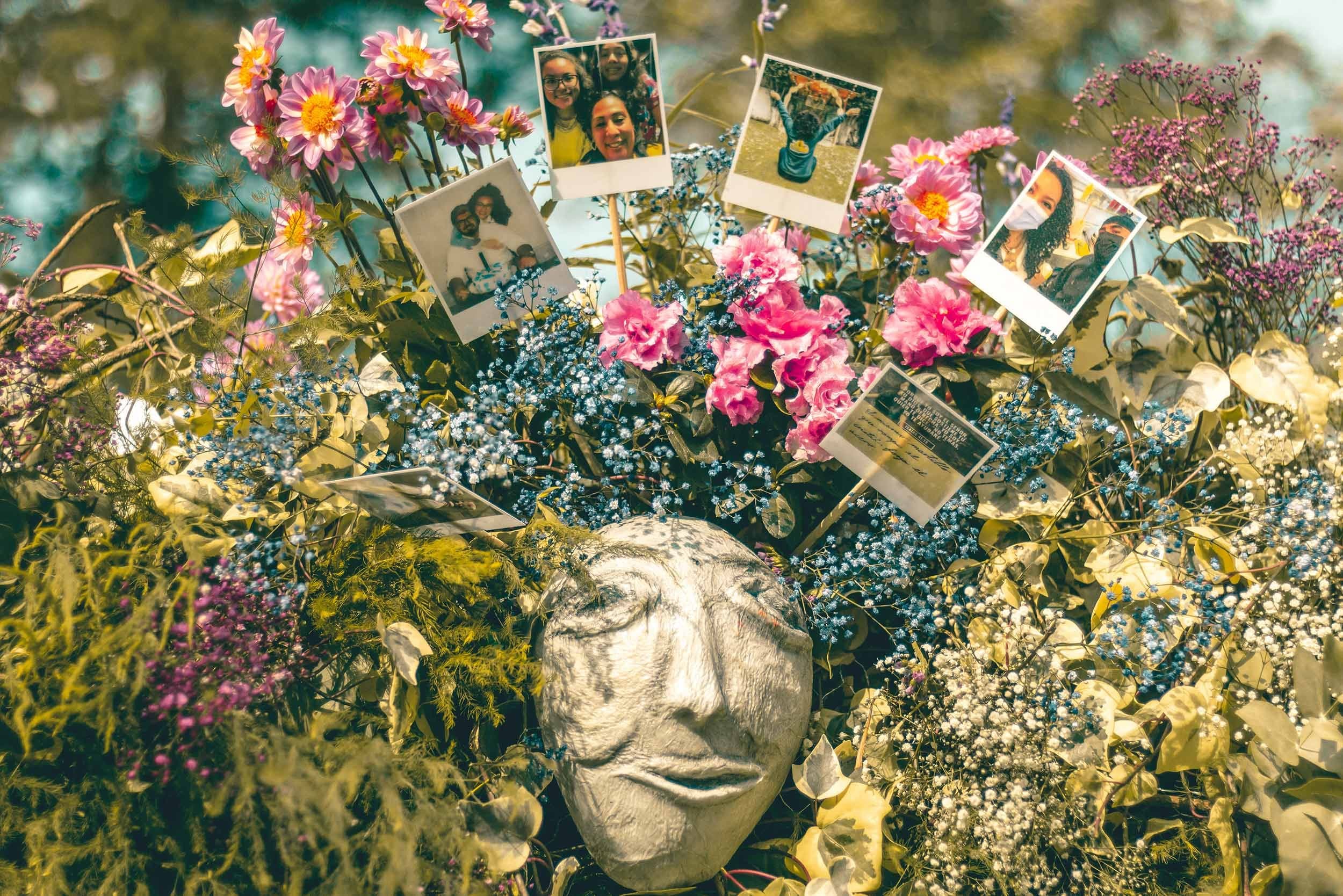 Detalle del rostro escultórico rodeado de flores y retratos