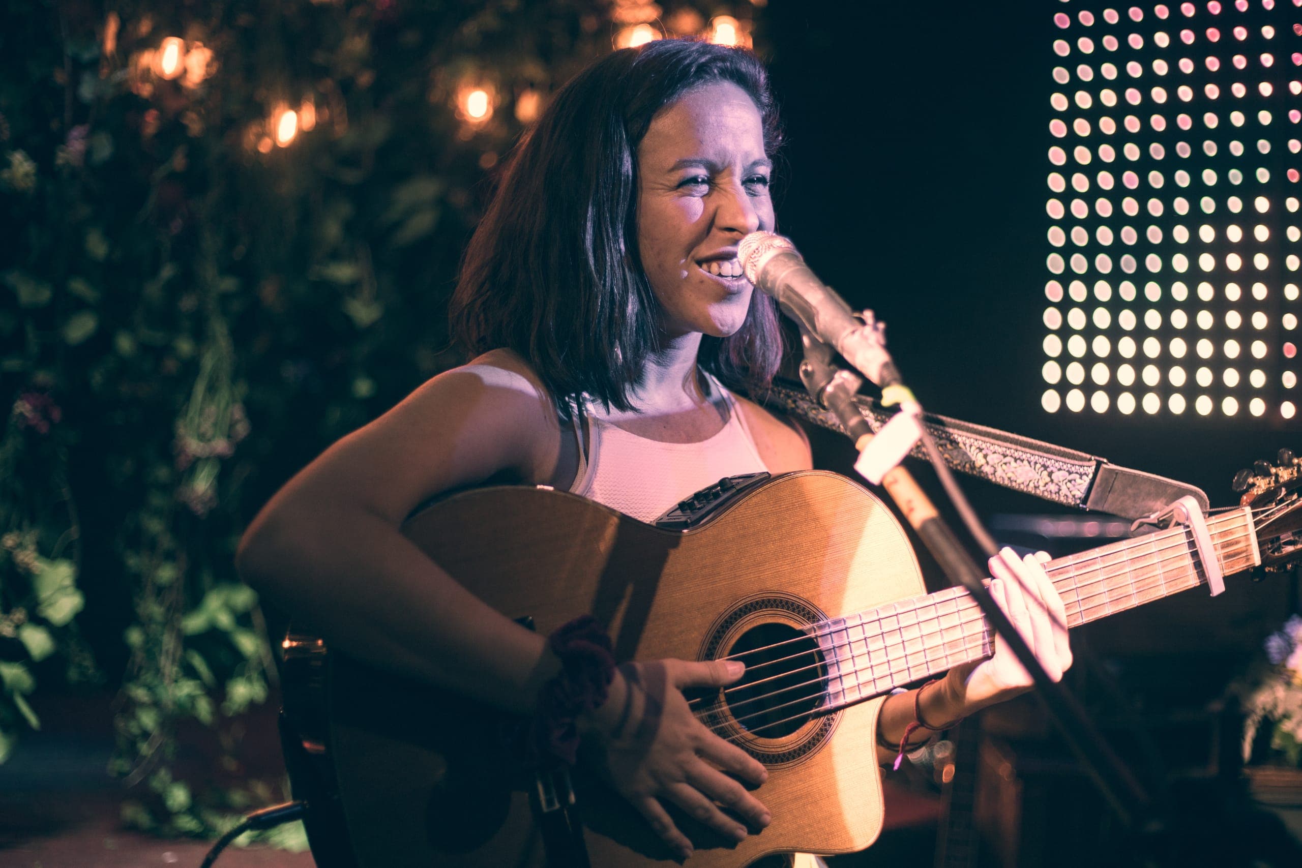 Cantante con guitarra sonriendo bajo las luces del foro