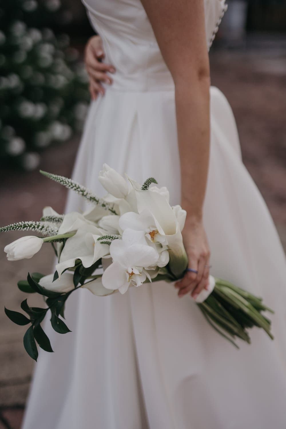 Ramo alargado de orquídeas y calas blancas al costado del vestido