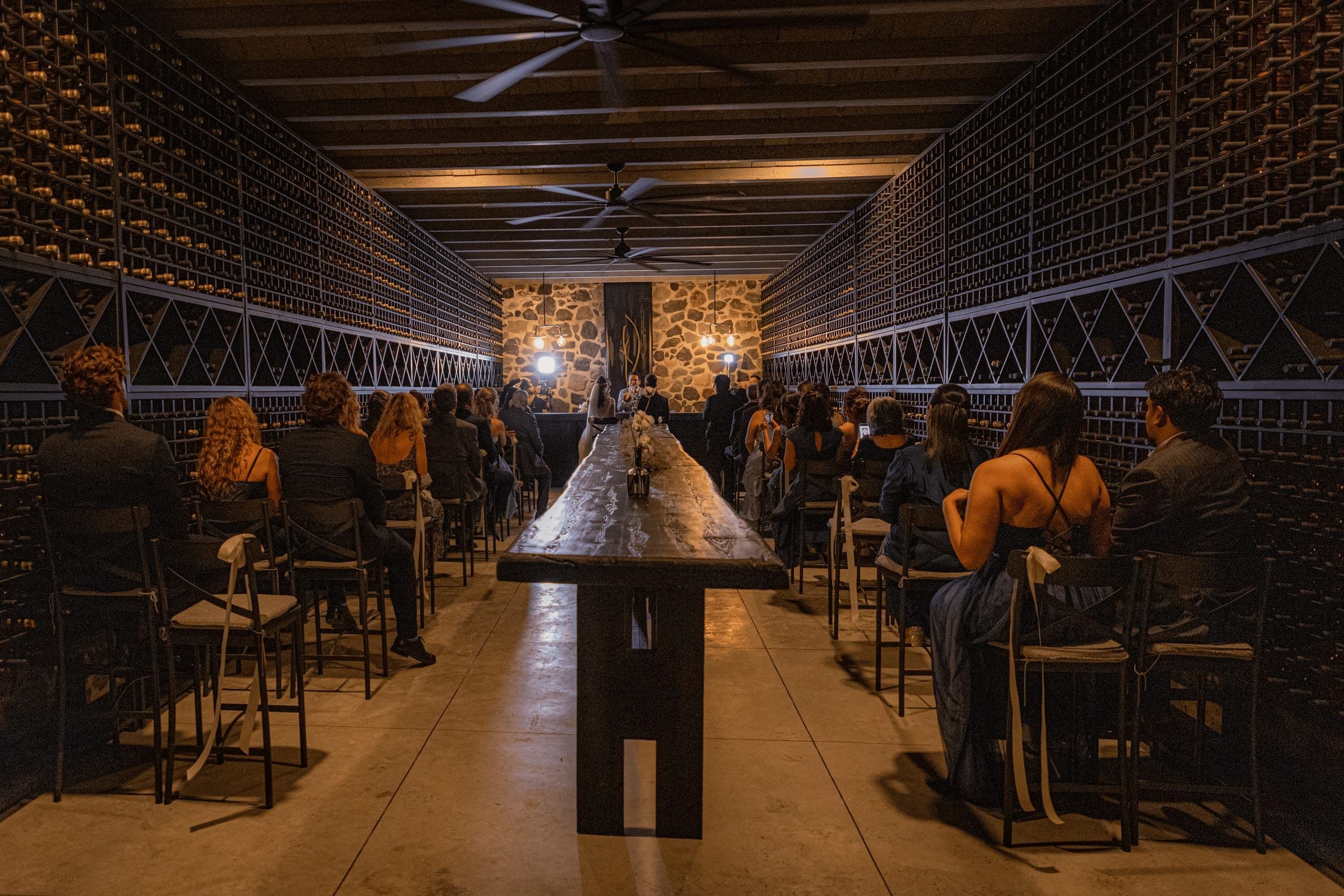 Cena en una cava con mesa larga de madera iluminada con velas