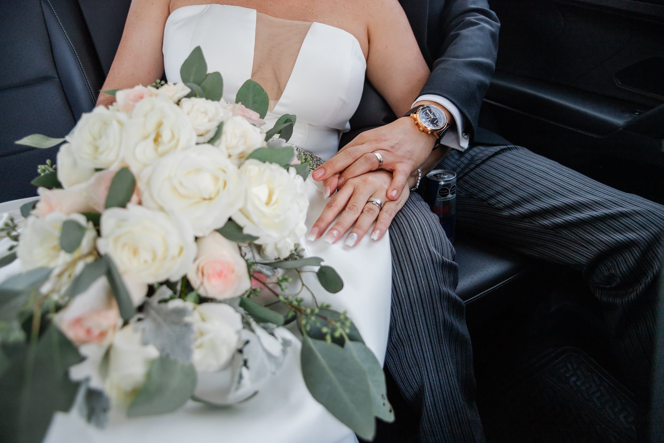 Novia con su ramo de rosas blancas y eucalipto, tomada de la mano del novio