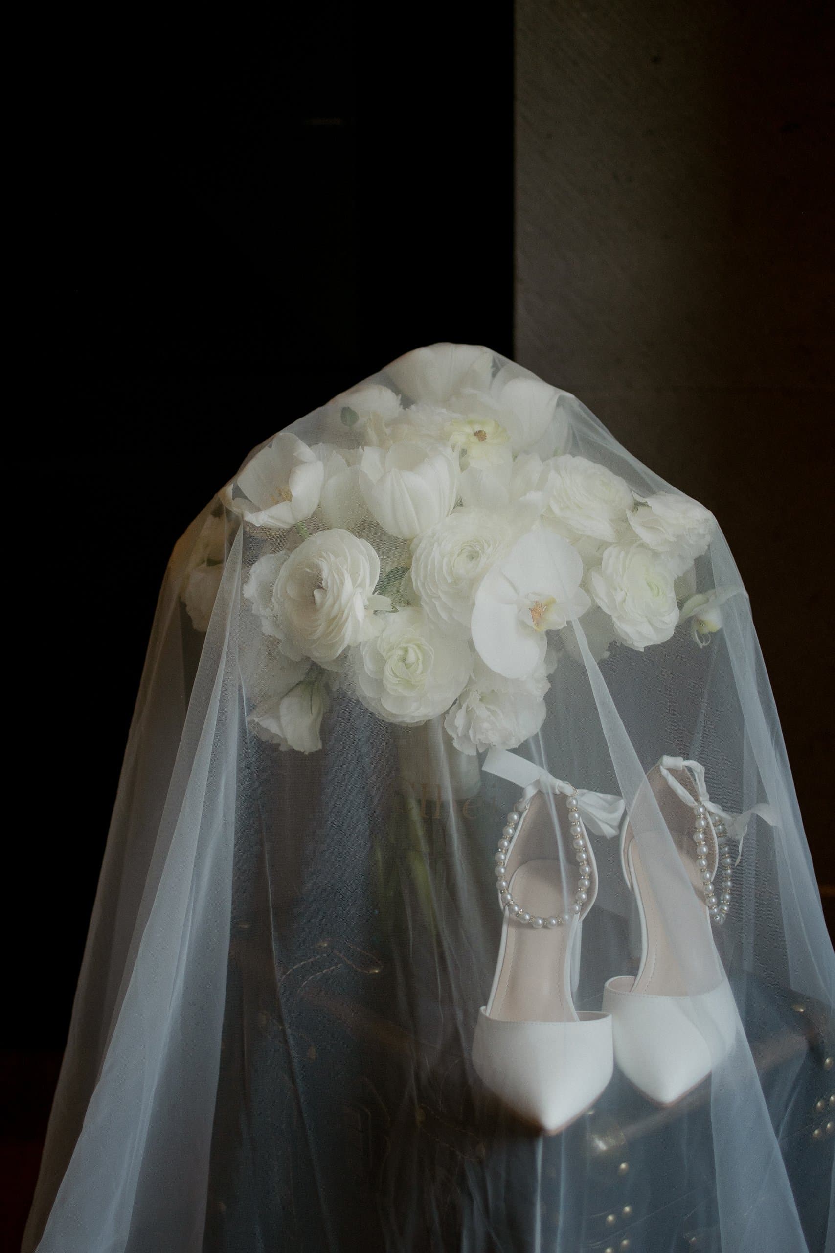 Ramo de ranúnculos blancos y zapatillas de novia bajo el velo, detalle del gran día por Clhei
