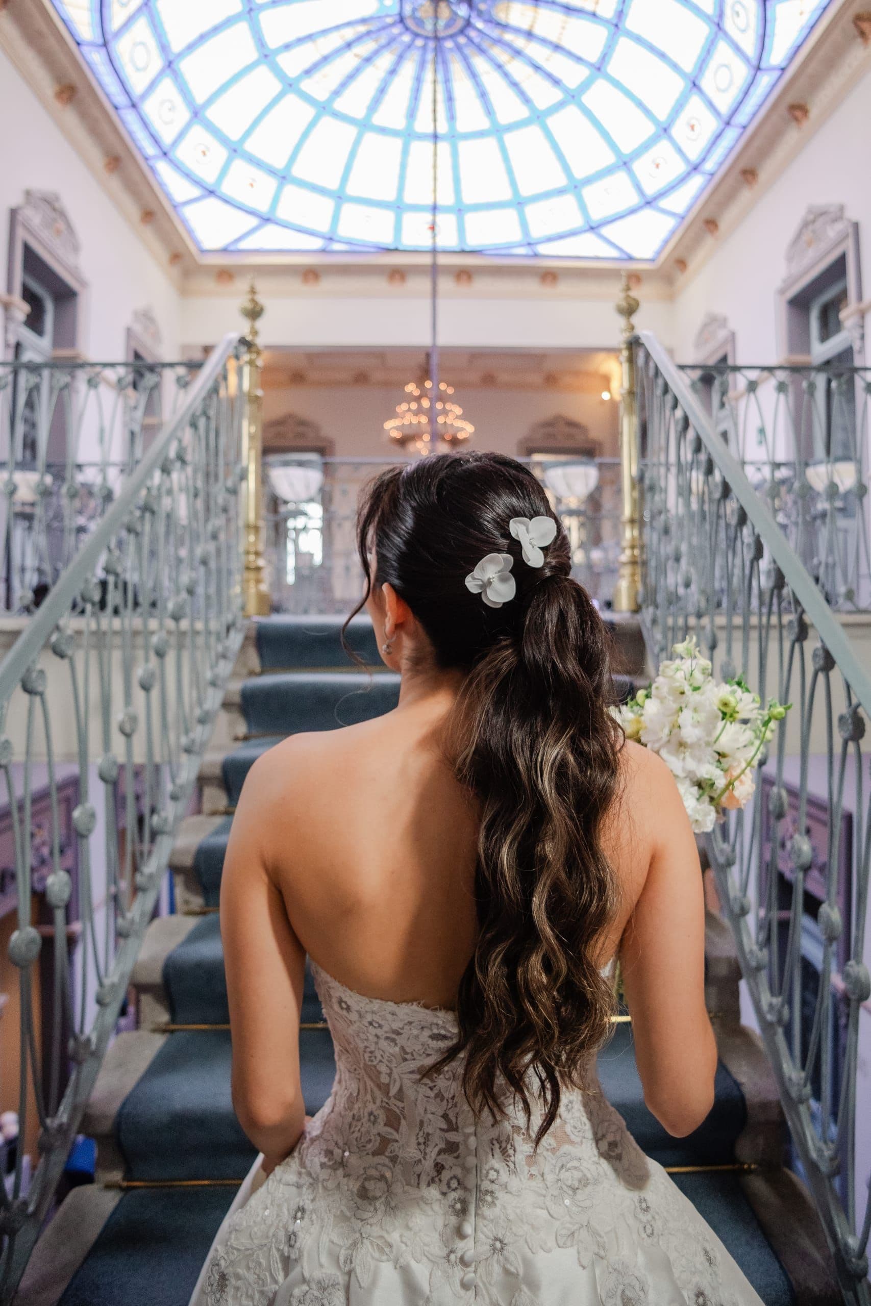 Bride seen from behind beneath the stained-glass dome of a historic mansion in Puebla