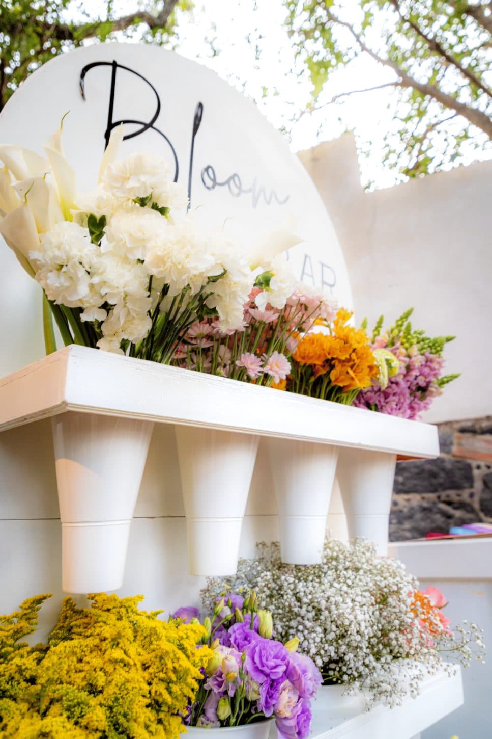 Close-up of Clhei's Bloom Bar: callas, white carnations and seasonal flowers arranged under the lettering